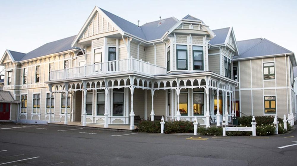 Das viktorianische Gebäude der Chilton Saint James School ist mit einer Veranda und dekorativen Details an einer Straße mit parkenden Autos zu sehen.