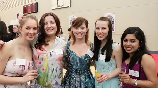 Eine Gruppe junger Schülerinnen der Chilton Saint James School posiert in farbenfrohen Kleidern vor einem Basketballkorb.
