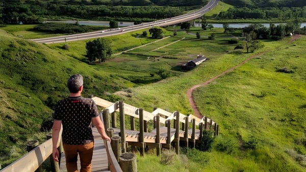 Eine Person steht auf einem Holzsteg und blickt auf eine grüne Landschaft mit Fluss und Straße auf dem Gelände der Chinook High School.