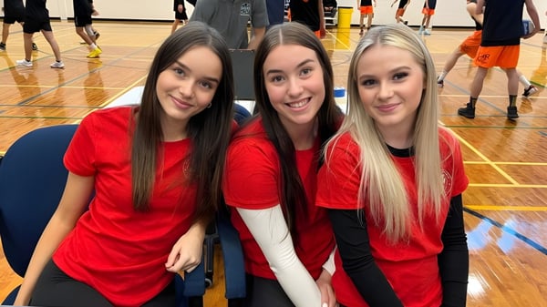 Drei Schülerinnen der Chippewa Secondary School in roten Shirts posieren in einer Turnhalle.