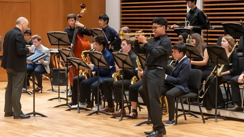 Ein Orchester der Choate Rosemary Hall spielt unter der Leitung eines Dirigenten auf der Bühne vor Publikum.