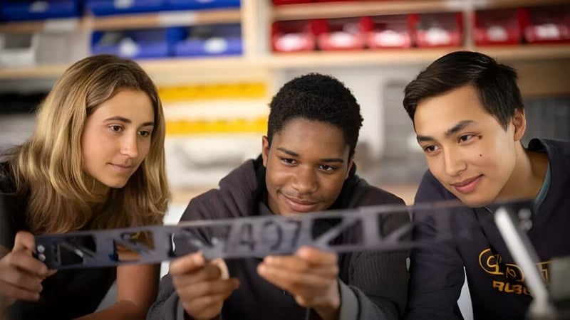 Drei Schüler der Choate Rosemary Hall betrachten gemeinsam ein Dokument in einem Klassenraum.