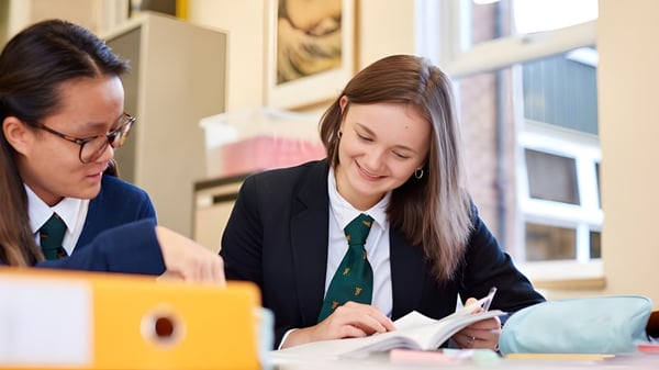 Zwei Schüler in Schuluniformen arbeiten gemeinsam an einer Aufgabe am Tisch im Christ College.