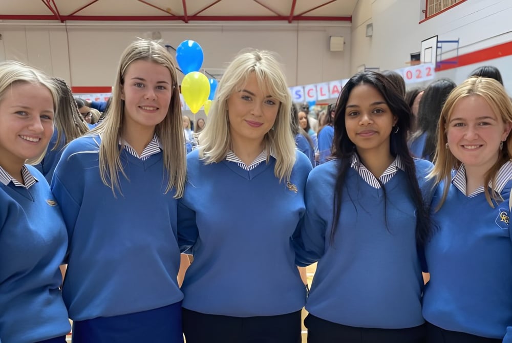 Fünf Schülerinnen der Christ King Secondary School stehen gemeinsam in einem Flur mit bunten Luftballons im Hintergrund.