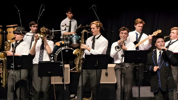 Schüler der Christchurch Boys High School treten in formeller Kleidung mit Trommeln und Saxophonen auf der Bühne auf.