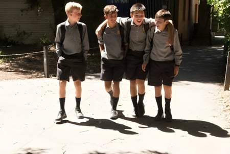 Eine Gruppe von Schülern steht im Außenbereich auf dem Campus der Christchurch Boys High School nahe einem Kiesweg und Büschen.