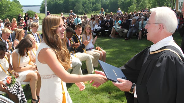 Eine Gruppe von Absolventinnen und Absolventen feiert die Abschlussfeier im Freien auf dem Campus der Christchurch School.