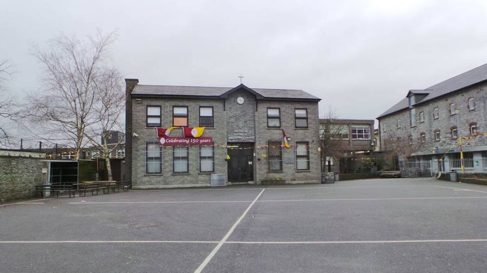 Das steinerne Hauptgebäude der Christian Brothers School Kilkenny mit mehreren Fenstern und gepflastertem Hof im Vordergrund.