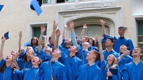 Schüler der Christian Central Academy feiern vor dem Schulgebäude ihren Abschluss in blauen Talaren.