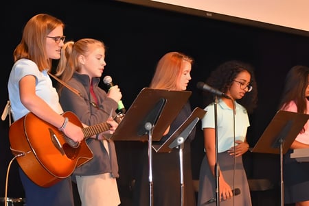 Schülerinnen der Christian Central Academy führen gemeinsam auf der Bühne ein Musikstück auf.