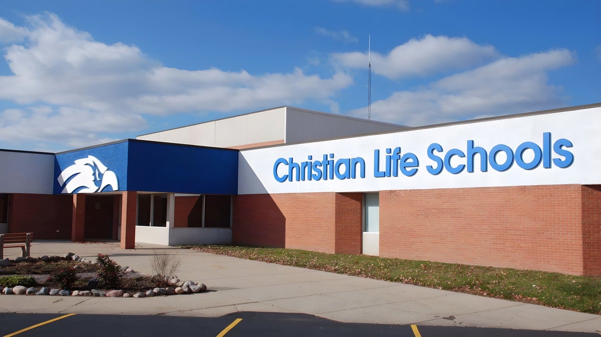 Das Gebäude der Christian Life School zeigt eine Ziegelfassade mit dem Schulschild vor blauem Himmel mit Wolken.