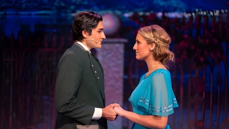 Zwei Personen halten auf der Bühne vor farbigem Hintergrund Händchen auf dem Campus der Christian Unified Schools.