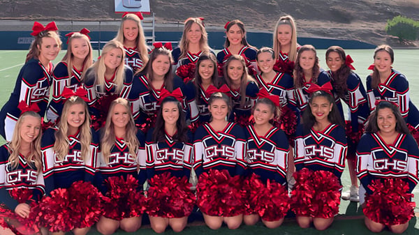 Eine Gruppe von Cheerleadern posiert mit einheitlichen Uniformen und Pompons auf dem Sportfeld der Christian Unified Schools.