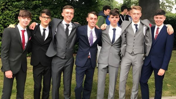 Eine Gruppe Schüler in formeller Kleidung steht im Grünen auf dem Campus von Christ's College.