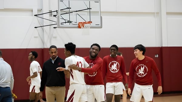Eine Gruppe Schüler der Church Farm School steht auf dem Basketballplatz neben einem Korb.