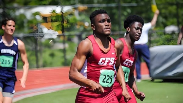 Zwei männliche Sportler laufen auf der Laufbahn der Church Farm School mit einem grasbewachsenen Feld und Bäumen im Hintergrund.