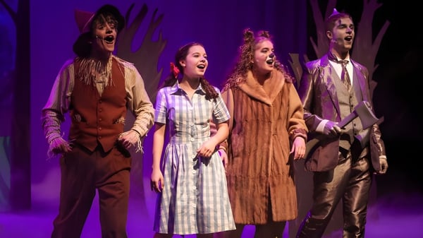 Eine Gruppe von vier Kostümierten führt auf der Bühne der Cincinnati Christian Schools vor einem violetten Hintergrund eine Aufführung auf.