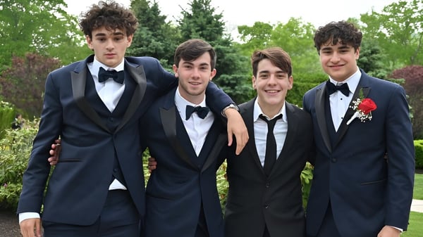 Eine Gruppe junger Männer in formeller Kleidung steht auf dem Campus des Cistercian College im Grünen zusammen.