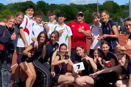 Eine Gruppe von Schülerinnen und Schülern der City of London Freemen’s School posiert auf dem Sportplatz unter blauem Himmel.