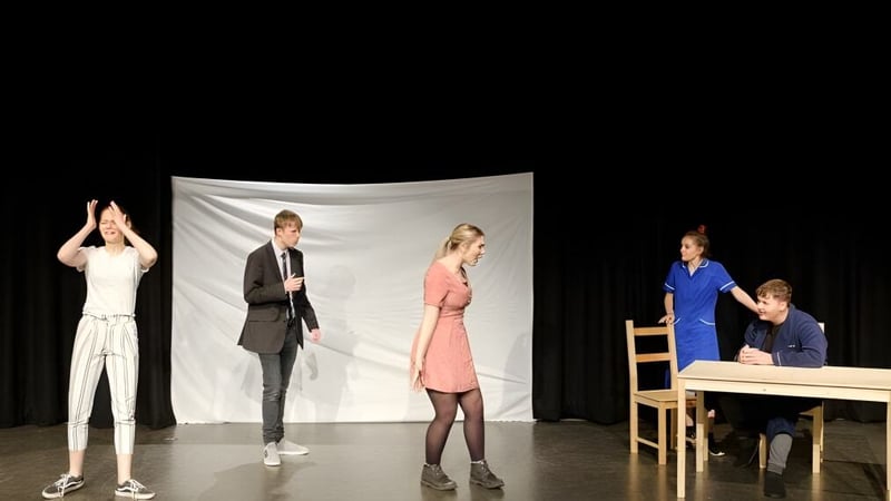 Schüler der City of London Freemen’s School führen ein Theaterstück auf einer Bühne mit unterschiedlicher Beleuchtung auf.