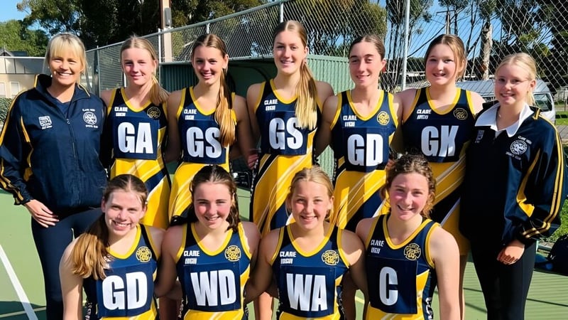 Eine Gruppe weiblicher Netballspielerinnen der Clare High School posiert gemeinsam auf dem Netballplatz.