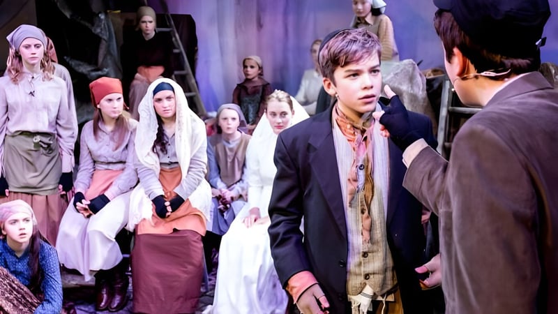 Eine Gruppe von Schülerinnen und Schülern der Claremont School steht auf einer Bühne in einem Aufführungsraum vor Vorhängen und Beleuchtung.