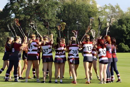 Eine Gruppe junger Sportlerinnen steht auf dem Sportfeld der Claremont School mit Bäumen im Hintergrund.
