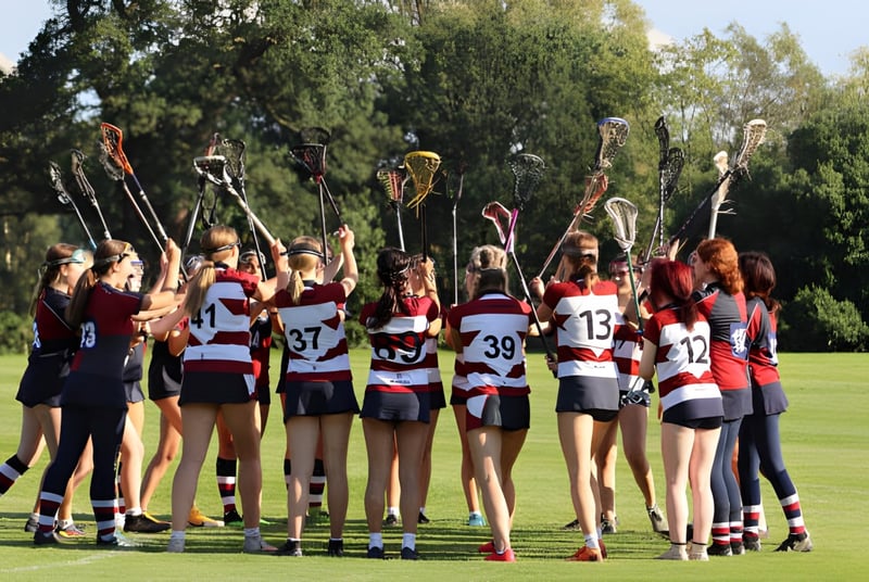 Eine Gruppe junger Sportlerinnen steht auf dem Sportfeld der Claremont School mit Bäumen im Hintergrund.
