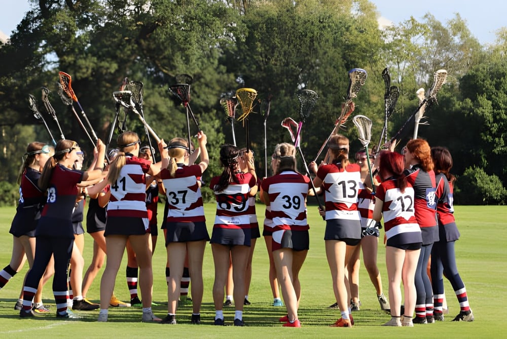 Eine Gruppe junger Sportlerinnen steht auf dem Sportfeld der Claremont School mit Bäumen im Hintergrund.