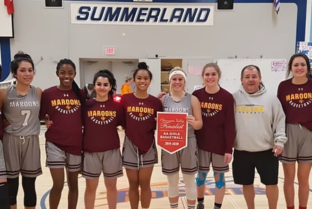 Schülerinnen der Clarence Fulton Secondary School stehen in Sportuniformen gemeinsam vor dem Schild Summerland.