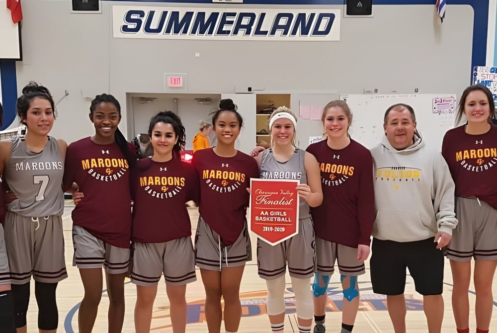Schülerinnen der Clarence Fulton Secondary School stehen in Sportuniformen gemeinsam vor dem Schild Summerland.
