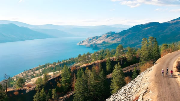 Ein gewundener Feldweg führt durch bewaldete Berge mit einem großen See im Hintergrund auf dem Gelände der Clarence Fulton Secondary School.