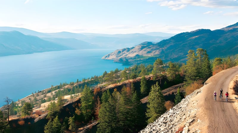 Ein gewundener Feldweg führt durch bewaldete Berge mit einem großen See im Hintergrund auf dem Gelände der Clarence Fulton Secondary School.