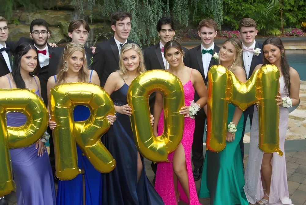 Schüler der Clarence High School posieren in formeller Kleidung mit großen goldenen Buchstaben vor einem Pool im Freien.