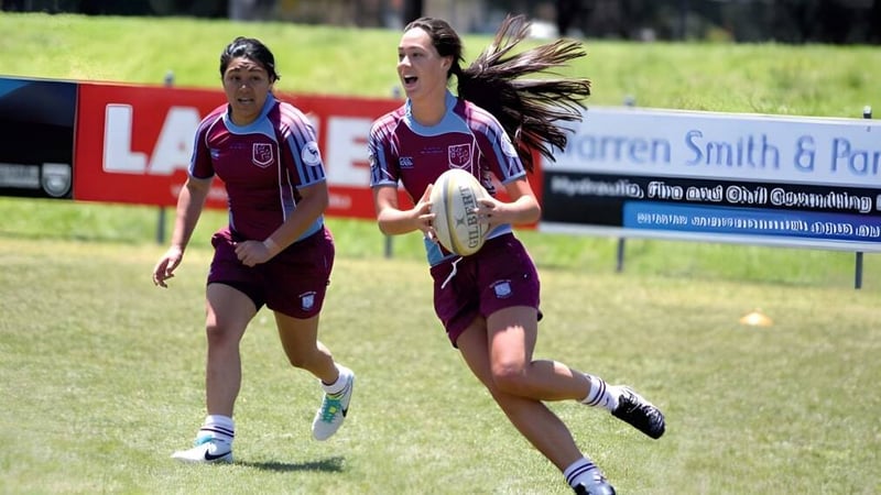 Zwei Rugby-Spielerinnen in maroon Uniform laufen über das Spielfeld der Clarence High School.
