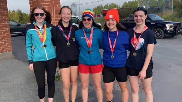 Eine Gruppe von fünf Sportlern mit Medaillen steht vor einem Backsteingebäude auf dem Gelände der Clarenville High School.
