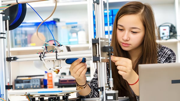 Eine Schülerin des Clarin College untersucht konzentriert ein Bauteil am 3D-Drucker.