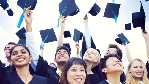 Eine Gruppe von Absolventen des Clarin College wirft ihre Abschlussmützen in den klaren Himmel.