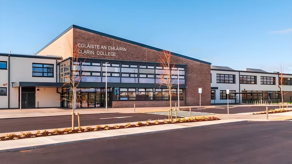 Das moderne Backsteingebäude des Clarin College mit großen Fenstern und einem sichtbaren Eingang ist von einem Garten umgeben.
