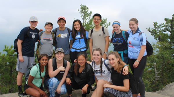 Eine Gruppe von Schülerinnen und Schülern des Clarin College posiert gemeinsam im Freien vor Bäumen und bewölktem Himmel.