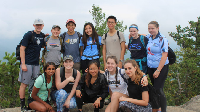 Eine Gruppe von Schülerinnen und Schülern des Clarin College posiert gemeinsam im Freien vor Kiefern.