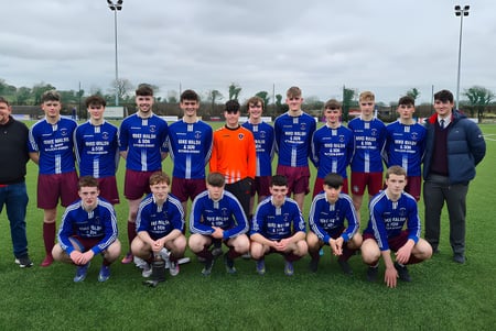 Eine Gruppe von Schülern des Clarin College posiert auf einem Rasenfeld vor bewölktem Himmel.