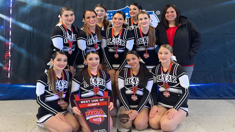 Eine Gruppe Cheerleader posiert in passenden schwarz-weißen Uniformen gemeinsam auf der Bühne im Clark County School District.