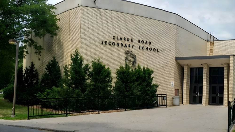 Das Backsteingebäude der Clarke Road Secondary School ist von Bäumen und einem Metallzaun umgeben.