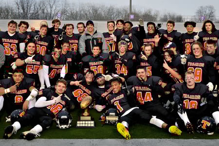 Eine Gruppe von Schülern der Clarke Road Secondary School steht zusammen auf einem Grasfeld vor Bäumen und Gebäuden.