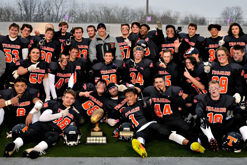 Eine Gruppe von Schülern der Clarke Road Secondary School steht zusammen auf einem Grasfeld vor Bäumen und Gebäuden.