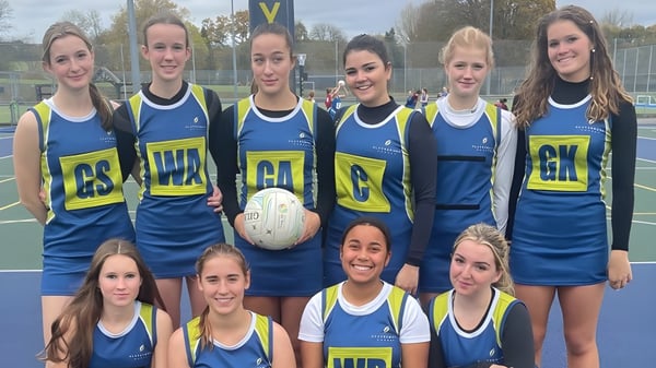 Eine Gruppe junger netballspielender Schülerinnen posiert gemeinsam auf dem Spielfeld der Clayesmore School.