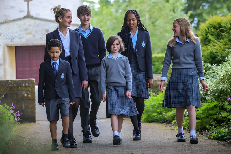 Schüler der Clayesmore School gehen gemeinsam auf einem Weg entlang üppiger Grünflächen mit einem Gebäude im Hintergrund.