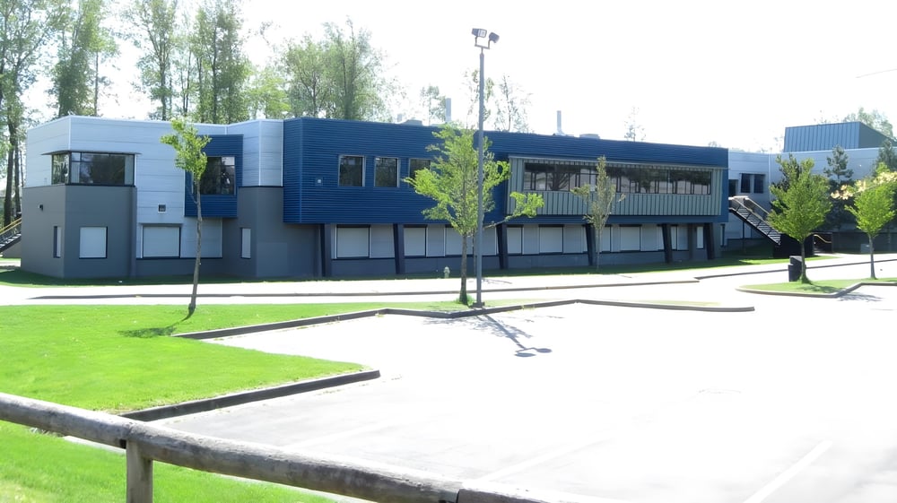 Das moderne mehrstöckige Gebäude der Clayton Heights Secondary School ist von Bäumen und einer Rasenfläche umgeben.