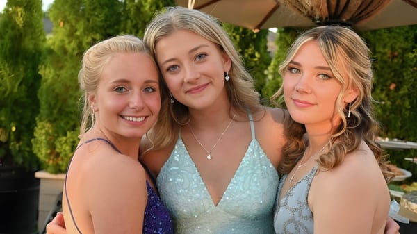 Drei Schülerinnen der Clayton Heights Secondary School posieren gemeinsam draußen vor grünem Baumhintergrund.